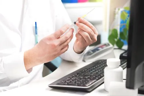 Pharmacist preparing a vaccine syringe at a pharmacy workstation