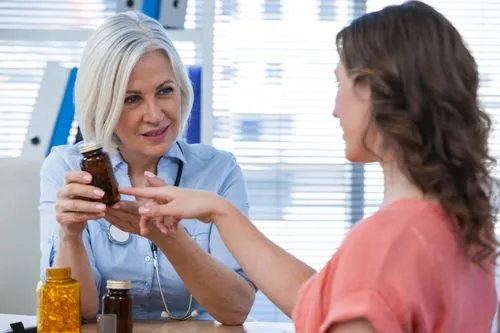 Pharmacist reviewing a medication bottle with a patient during a consultation