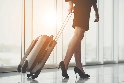 Traveler walking through an airport terminal with a rolling suitcase